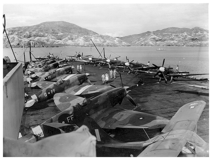 Spitfire Mk.XIVs of No 132 (City of Bombay) Squadron RAF aboard SMITER in Hong Kong Harbour, September 1945. There is also a single Stinson Reliant communications aircraft (nearest camera).   Photo: Courtesy of Terry Oxley
